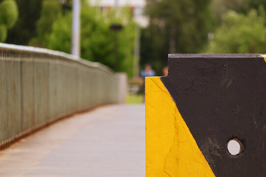 Close-up of a yellow and black wheel stop with a visible mounting hole and cracked paint