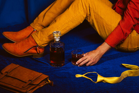 A tired office worker drinks whiskey on a blue velvet floor
