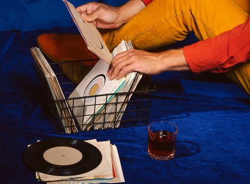 Male music lover searches through vinyl record collection indoors