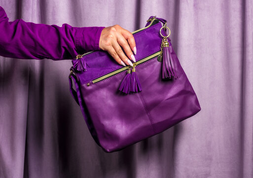 Woman holds a purple bag against a matching curtain indoors