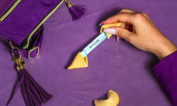 Female hand opens a fortune cookie with a no future message