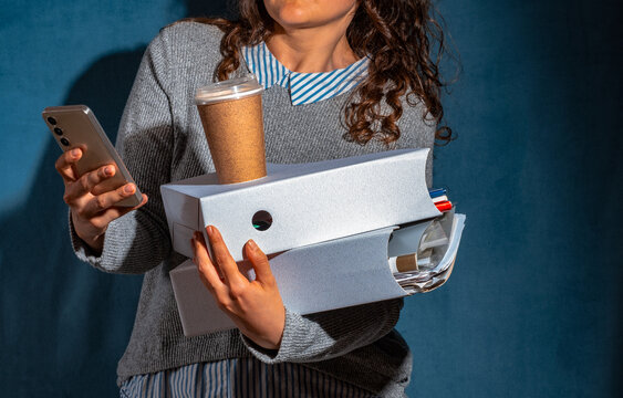 Overwhelmed woman holds smartphone folder and coffee indoors