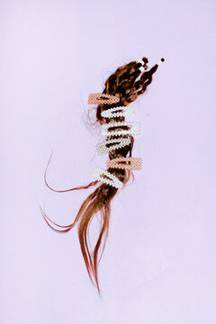 A brown hair extension features multiple pearl clips on a background