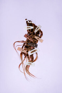Cut brown hair extension with pearl accessory on plain background