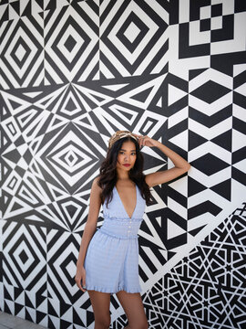 A stylish woman poses against a black and white geometric wall