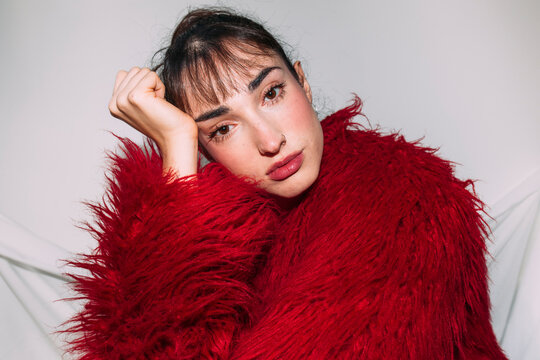 Woman in red faux fur coat looks at camera during editorial shoot