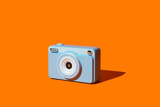 A blue instant camera casts a shadow on an orange backdrop