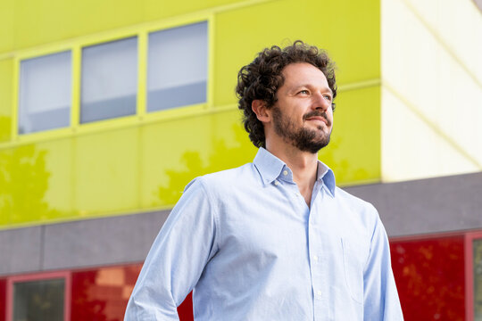 Confident businessman stands outdoors near a modern colored wall