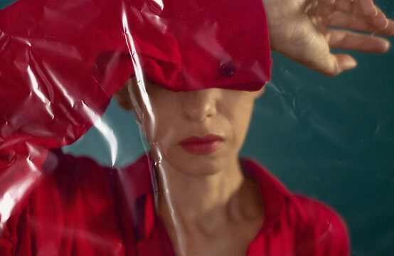 A woman stands behind a plastic film to show environmental pollution