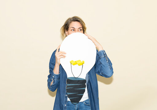 Woman holds a paper lightbulb symbolizing creativity and energy