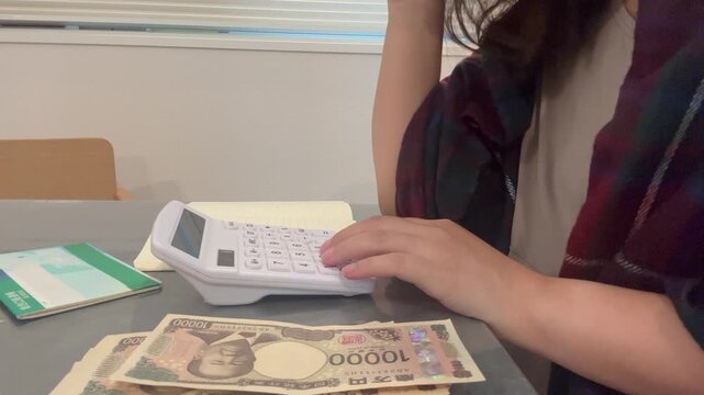 電卓を叩きながら首を横に振る女性