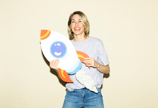 Smiling woman holds a handmade paper rocket symbolizing business growth
