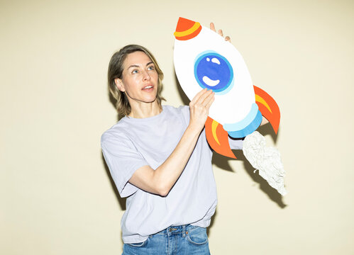 Woman holds a handmade paper rocket indoors for business growth