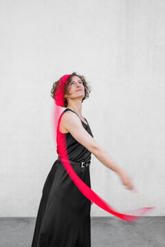 Woman in black dress twirling a red ribbon with dynamic movement