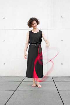 Mid adult caucasian woman in black dress standing barefoot with red ribbon