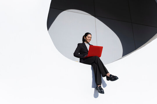 Businesswoman with red laptop working outdoors in Barcelona