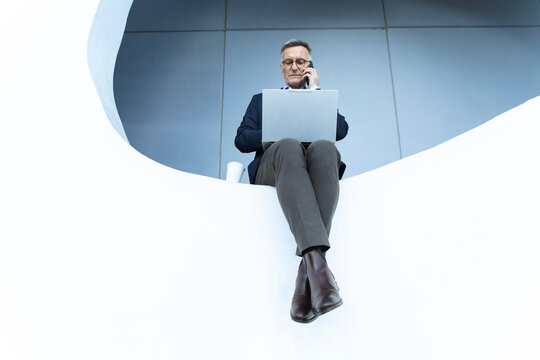 Business professional multitasking with laptop and phone outdoors in Barcelona