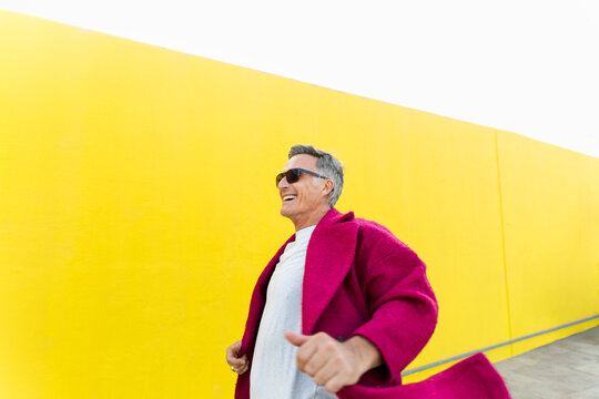 A happy man walks past a vibrant yellow wall