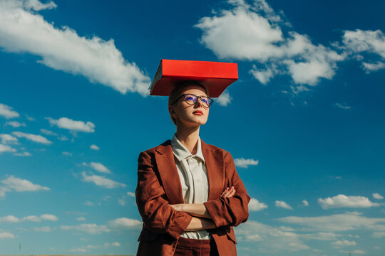 Businesswoman balancing a red folder on her head outdoors