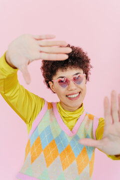 Smiling young woman gesturing with hands in front of pink background