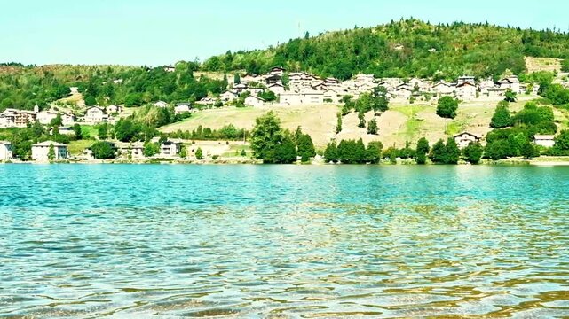 Water movement of Lake Serraia, in Trentino, also with views of the surrounding mountains under a blue sky