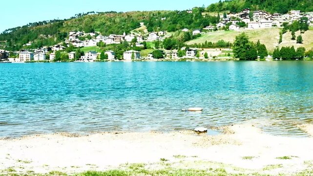 Water movement of Lake Serraia, in Trentino, also with views of the surrounding mountains under a blue sky