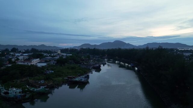 Banda Aceh, Indonesia : Forward aerial drone footage of riverside residential and trawler fishing baot in Banda Aceh  river of Sumatera, Indonesia with volcano in the background at sunset