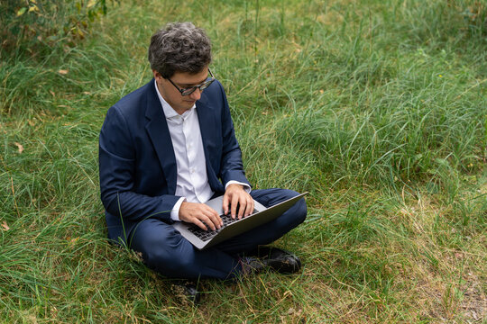 Man working remotely on a laptop in a green meadow, combining fr