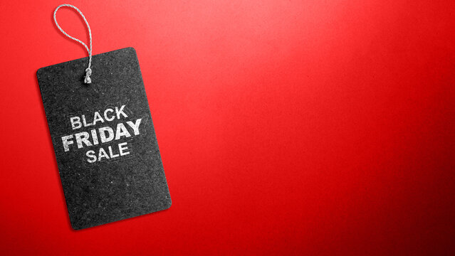 Black price tag with 'Black Friday Sale' text on a textured red background with copy space. Concept of Black Friday
