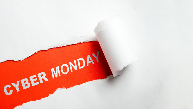 Cyber Monday text on red background revealed through torn white paper. Creative holiday shopping sale concept. Concept of Cyber Monday sale