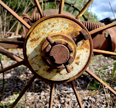 Close-up of vintage rusted agricultural machine wheel hub with cotter pin and spoke design