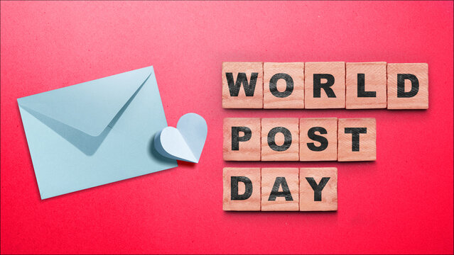 World Post Day flat lay composition with wooden letter blocks, a blue envelope, and a paper heart on a red background. Concept of World Post Day
