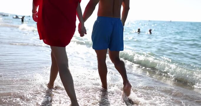 A delightful couple splashes through the gentle waves at a sunny beach. Hand in hand, they enjoy each other's company, creating lasting memories in the shimmering sand.