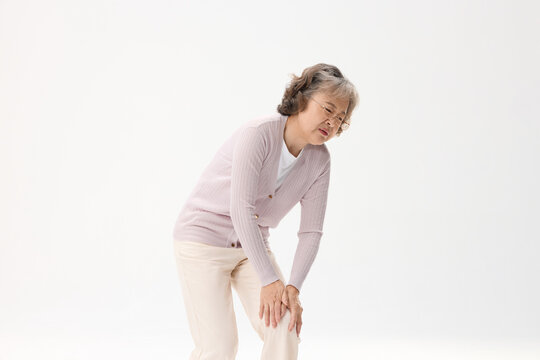 Senior woman in pain from knee discomfort, leaning forward