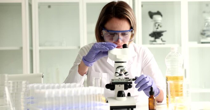 In a bright laboratory, a focused woman examines samples under a microscope, showcasing the passion for discovery and learning in modern science.