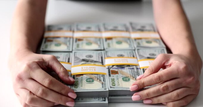 Hands carefully arrange bundles of cash on a clean table. The bright setting emphasizes the neat stacks, showcasing wealth and meticulous organization.