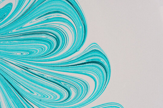 Turquoise abstract paint fan pattern on white background with ample negative space for text.