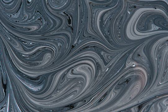 Abstract dark grey and black liquid swirl pattern with smooth marbled paint texture background.
