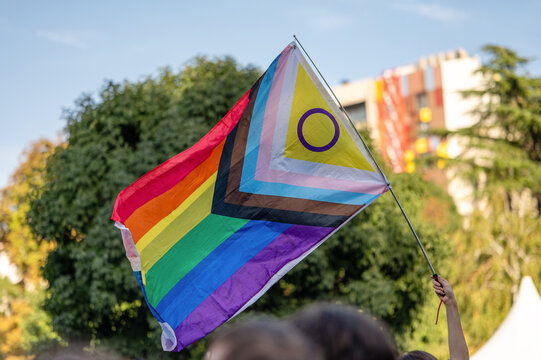 Rainbow Pride Flag with Intersex Symbol Against Blue Sky