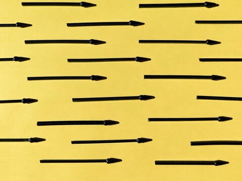 Black arrows arranged in rows on a yellow background. Directional symbols, navigation pattern, geometric composition.