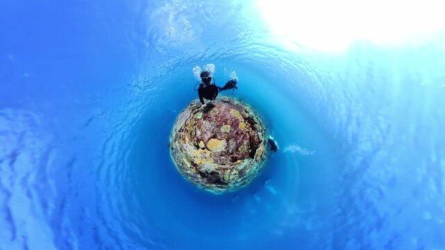 Creative tiny planet effect turns underwater 360 footage into a curved miniature world, showing a diver swimming above a coral reef beneath the ocean surface.