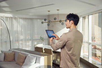 Man controlling smart home system with tablet in modern apartment © LeNgoc