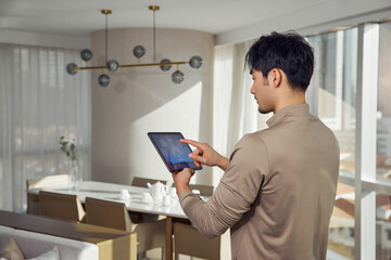 Man Using Tablet to Control Smart Home Appliances © LeNgoc