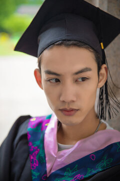 Graduate in Cap and Gown Leaning on Stone Wall