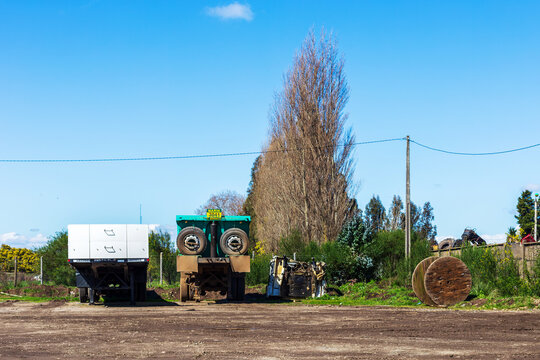 A rugged worksite in Angol, Chile featuring a parked dump truck, scattered machinery, and earthy rural surroundings under a clear sky