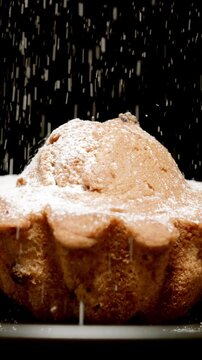 Powdered sugar falls on a fresh cupcake on a black background