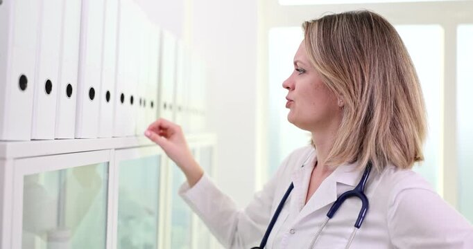 A healthcare professional navigates through neatly arranged folders in a sunny office, striving to find important patient information. Her focused expression reflects determination.