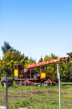 A stationary red‑boom crane with a yellow cabin sits on a grassy fenced area in Angol, Chile