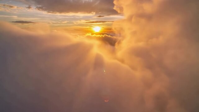 Golden sunbeams pierce through fluffy clouds during a serene sunrise aerial view