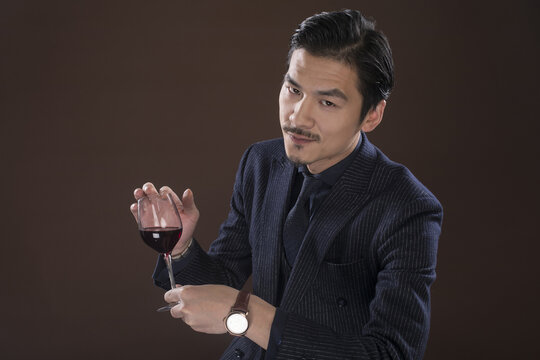 Man in suit holding red wine glass